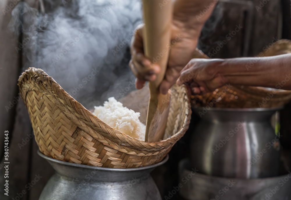 Hands of a person in the kitchen cook sticky rice with pot and rice