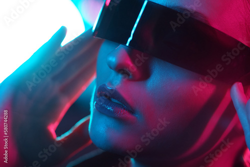 Portrait of a beautiful and young girl in cyberpunk style. Mixed color light effect. Futuristic concept with flares.