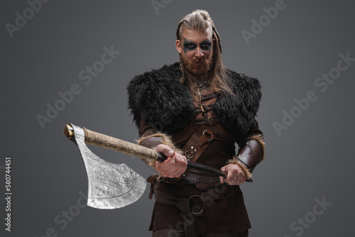 Shot of fearful barbarian from north dressed in black fur and holding huge axe.