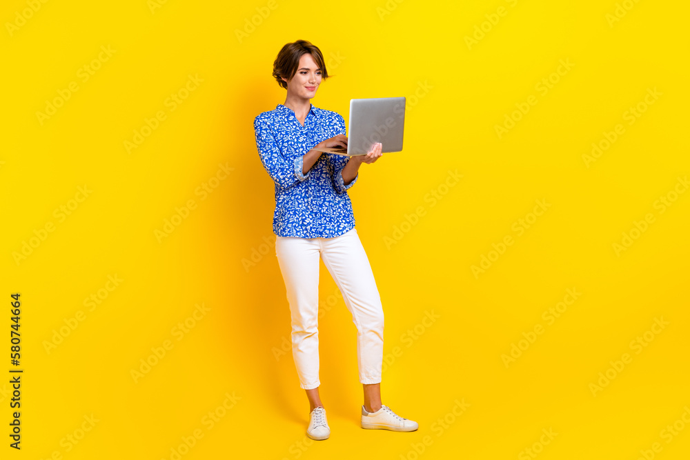 Full length photo of confident shiny woman dressed blue blouse chatting modern gadget isolated yellow color background Full length photo of confident shiny woman dressed blue blouse chatting modern gadget isolated yellow color background