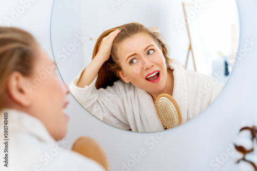 woman looking at scalp in mirror photo