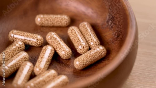 Herbal supplement capsules with milk thistle herb particles in wooden container for liver treatment and detoxification