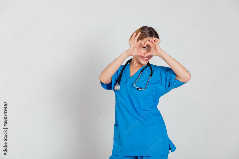female doctor in blue suit with stethoscope in hospital shows heart female doctor in blue suit with stethoscope in hospital shows heart