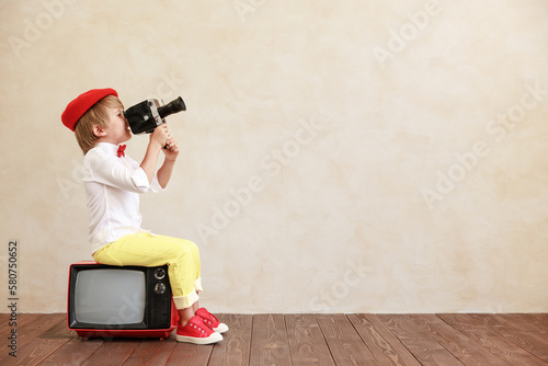 Bild auf Leinwand Funny boy holding vintage camera against grunge wall background