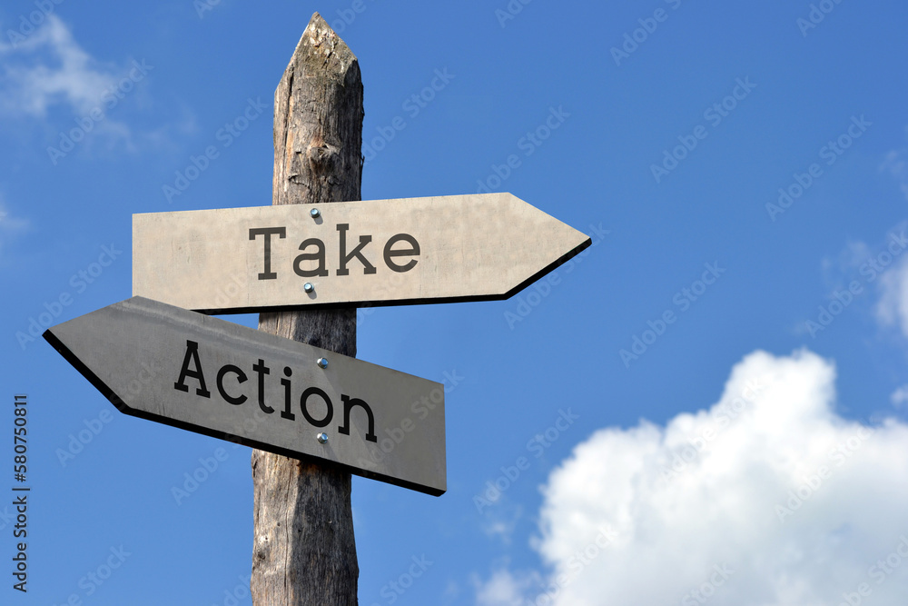 Take action - wooden signpost with two arrows, sky with clouds