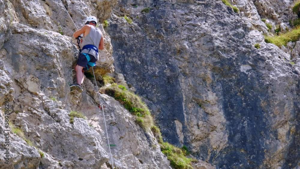 mature man, rock climber in body harnesses feature life-safety, attaches hooks to iron brackets, extreme lifestyle of people, mountaineering, via ferrata in mountains, life insurance in extreme sports mature man, rock climber in body harnesses feature life-safety, attaches hooks to iron brackets, extreme lifestyle of people, mountaineering, via ferrata in mountains, life insurance in extreme sports