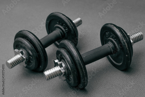 Fitness background. Two 10 kg dumbbells on a gray mat. Sports concept - gray mat, two black dumbbells 10 kg