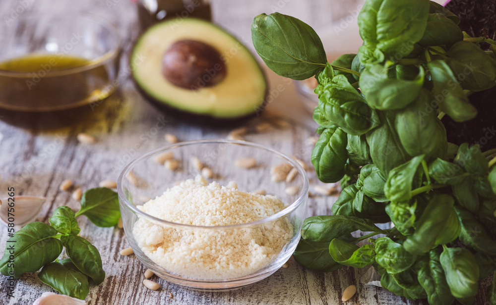 Basil, pine nuts, garlic, olive oil, parmesan and avocado on a kitchen table. Ingredients for Pesto recipe Basil, pine nuts, garlic, olive oil, parmesan and avocado on a kitchen table. Ingredients for Pesto recipe