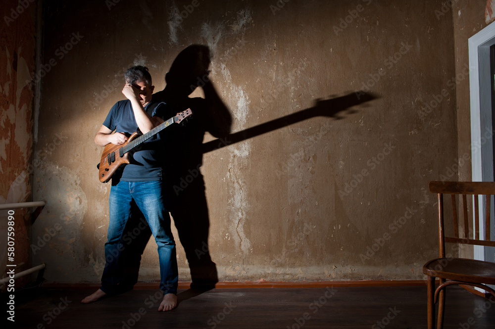Male musician with an electric guitar on the background of an old wall.