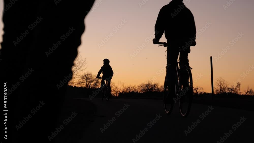 Zwei Jungs fahren mit dem Fahrrad an einem schönen Sommerabend in Richtung Horizont Zwei Jungs fahren mit dem Fahrrad an einem schönen Sommerabend in Richtung Horizont