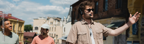 Εκτύπωση καμβά tour guide in sunglasses and headset pointing with hand during excursion on Andrews descent in Kyiv, banner