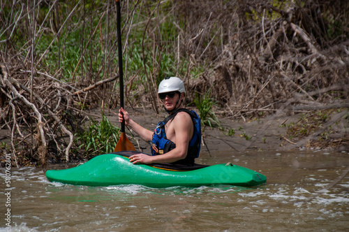 A man in a white water kayak gives a high sign with his paddle upstream
