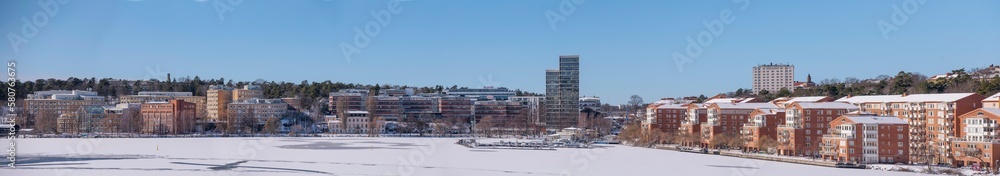 The bay Alviks Strand with waterfront apartment an office buildings, a snowy sunny spring day in Stockholm