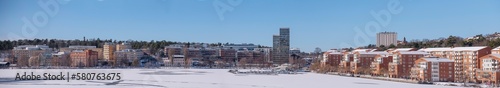 The bay Alviks Strand with waterfront apartment an office buildings, a snowy sunny spring day in Stockholm