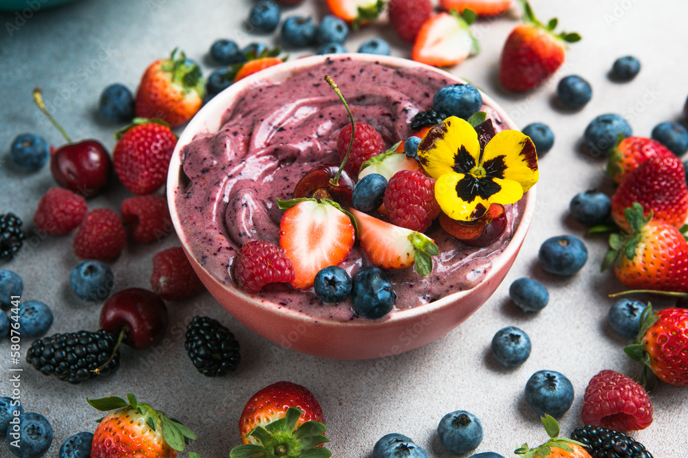 Two summer acai smoothie bowls with strawberries, blueberries, on gray concrete background. Breakfast bowl with fruit and cereal, close-up, top view, healthy food Two summer acai smoothie bowls with strawberries, blueberries, on gray concrete background. Breakfast bowl with fruit and cereal, close-up, top view, healthy food