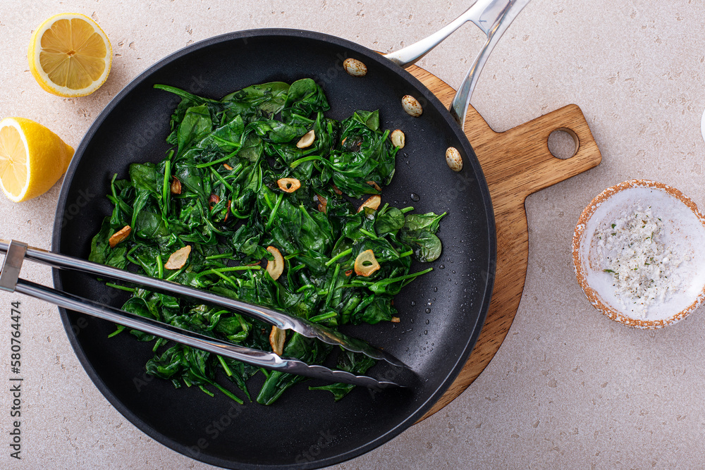 Sauteed spinach with garlic in a skillet - obrazy, fototapety, plakaty 