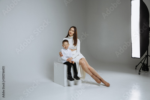 A little boy with his mother on a gray background of a photo studio