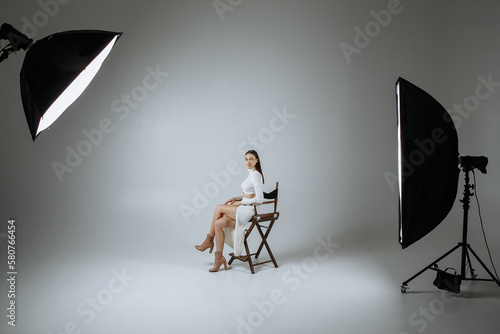 A girl in white clothes on a gray background of a photo studio
