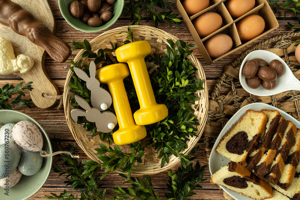 Gym dumbbells in traditional Easter Paschal wicker basket. Healthy diet