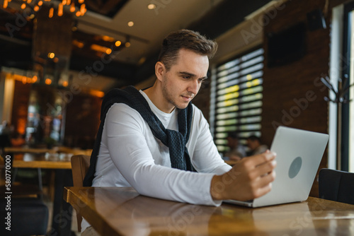 one man work on the computer laptop while sit at cafe or restaurant