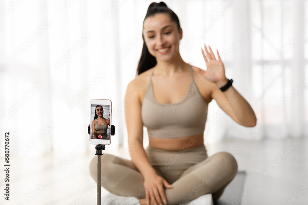 Selective focus on cell phone recording female fitness coach
