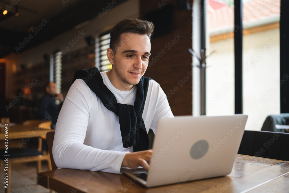 one man work on the computer laptop while sit at cafe or restaurant one man work on the computer laptop while sit at cafe or restaurant