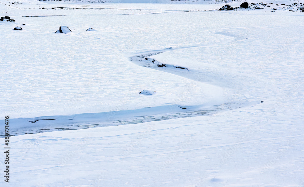 Snow covered frozen lake and winding stream