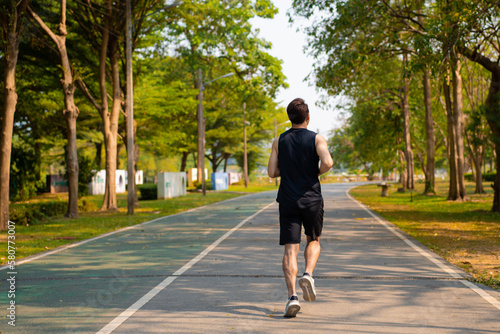 happy young Asian handsome man enjoys his running  in city public park during a summer day, sporty guy spend quality time on weekend jogging outdoor in nature for healthy and active lifestyle