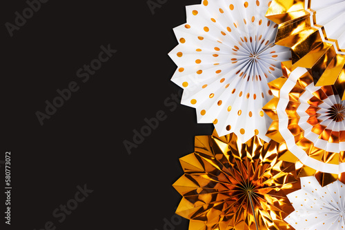 Gold colored paper fans on a black background with place for text.