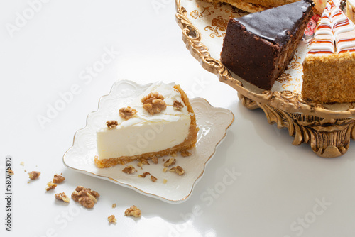different pieces of cake on golden vintage plate on white table