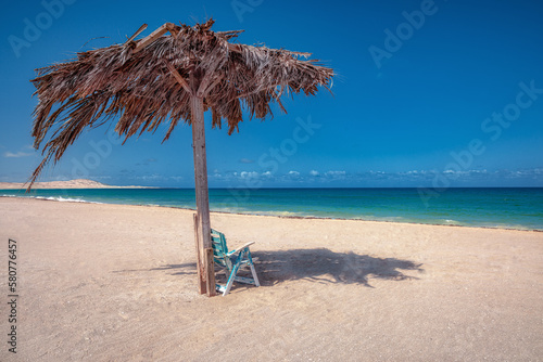 Summer beach scene with chair and smooth blue sea © tom-pic-art
