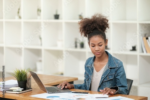 Smart African women working in beautiful office, working on Laptop, use the phone, talking on the cellphone. 