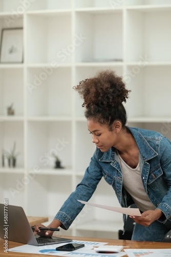 Smart African women working in beautiful office, working on Laptop, use the phone, talking on the cellphone.  © Treerat