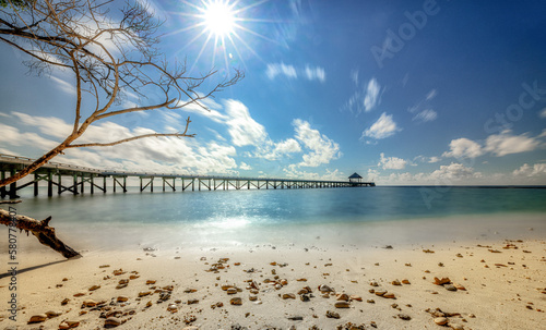 Beautiful landscape with bridge to the beach. Color fusion of ocean and sky. Gentle waves on amazingly clear water. Beautiful long exposure with sun star. Fine beach with small wet stones. Relax,rest © tom-pic-art