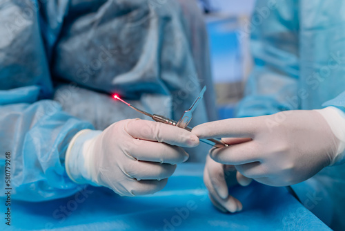 Professional doctors surgeon proctologist holding scalpel and anoscope in operation room at hospital. Medical and pharmaceutical concept. Scalpel surgeon's scissors, just before surgery photo