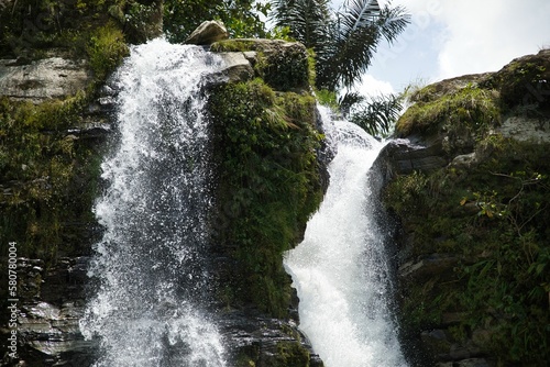 The spectacular Air Terjun Tengkulese waterfall on Flores, surrounded by sunlit rainforest.