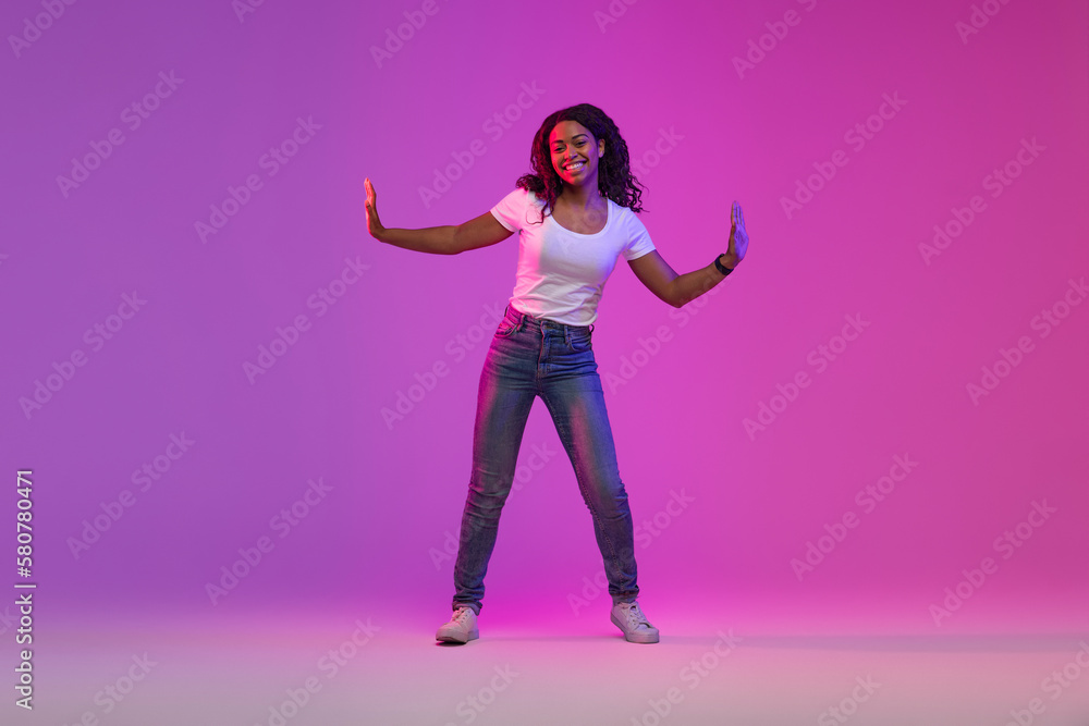 Joyful African American Female Dancing In Neon Light Over Purple Background