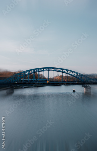 iron bridge over river with tram and autumn colors with motion blur.
