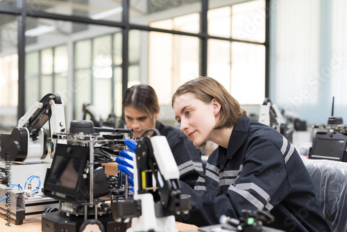 Two female engineers building and testing AI Robot and Artificial Intelligence of Things  AIoT  service robot in the manufacturing automation and robotics workshop