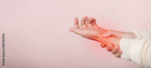 Young asian woman with white sweater cloth suffering from wrist hand pain injury. Causes of hurt include carpal tunnel syndrome, fractures, arthritis or trigger finger. world health day concept.