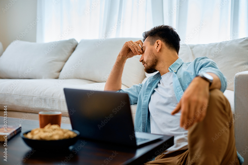 Distraught man having headache while using laptop at home. Distraught man having headache while using laptop at home.