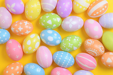 Happy easter holiday celebration concept. Group of painted colourful eggs decoration on a yellow background. Seasonal religion tradition design. Top view, flat lay, copy space.