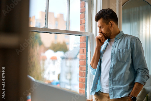 Photos Distraught man looking through window at home.