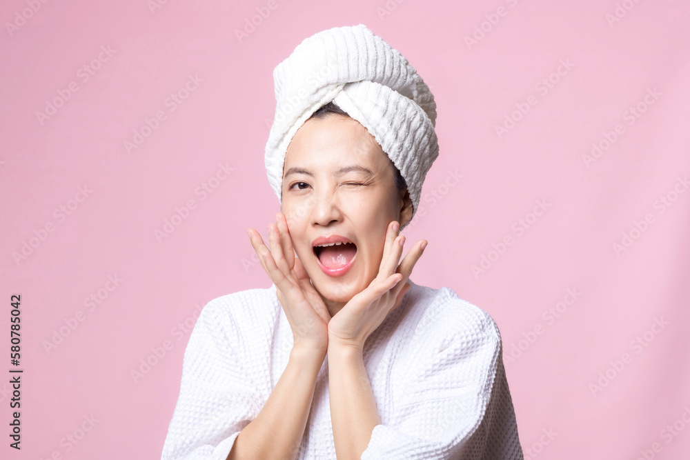 Beautiful young asian woman happy with clean face skin in towel and bathrobe, spa suit on pink background. Skincare, treatment, wellness therapy, facial care, beauty female health, cosmetology concept Beautiful young asian woman happy with clean face skin in towel and bathrobe, spa suit on pink background. Skincare, treatment, wellness therapy, facial care, beauty female health, cosmetology concept