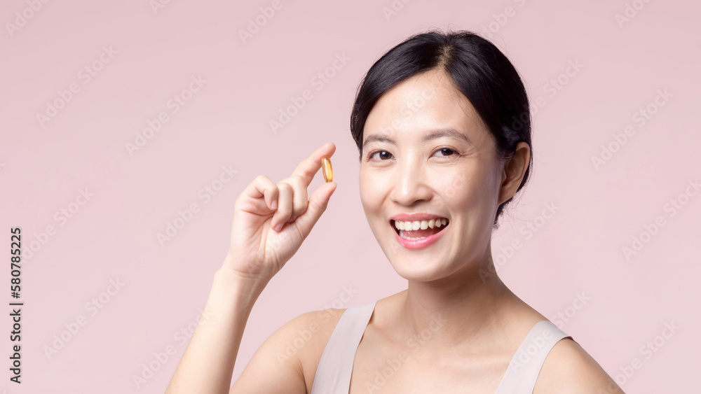 Portrait young asian woman happy smile face with vitamin nourishment pill. Pretty cute girl female person holding health capsule supplement skin care isolated on pink background. Medication concept. Portrait young asian woman happy smile face with vitamin nourishment pill. Pretty cute girl female person holding health capsule supplement skin care isolated on pink background. Medication concept.