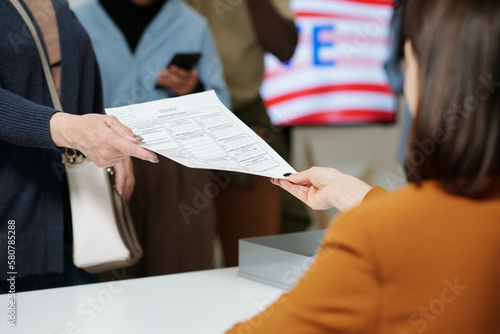 Billede på lærred Close-up of young woman from electoral commission passing ballot paper to one of