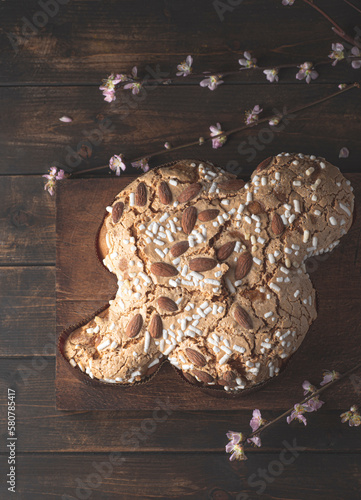 Сolomba pasquale - Italian sweet Easter bread or cake with almonds and powdered sugar and candied fruits. The baked dove is a symbol of Christ and the Easter holiday. Rustic wooden background