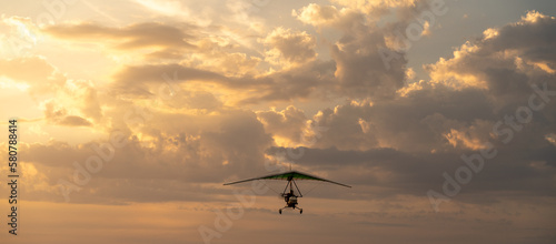 Propeller plane flies in the sunset sky. Banner, A small private hang-glider in a cloudy sky.