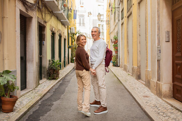 Happy Mature Couple Traveling Standing With Backpack Holding Hands Outside