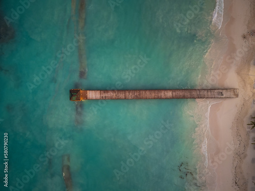 Top view of a wooden pier in the sea. White sandy beach. light turquoise sea water. Minimalism. Abstraction. There are no people in the photo. nature, ecology, recreation. © Anton